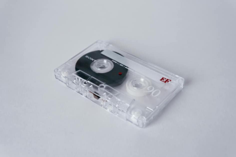 Close-up of a vintage cassette tape with clear casing on a white background, highlighting audio nostalgia.